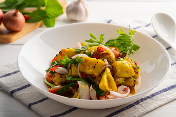 Thai Spicy Squid Salad,Grilled squid with onion and tomato in chilli lime sauce in white plate.Thai food.(yum pla muk yang)