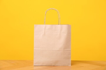 One kraft paper bag on wooden table against orange background