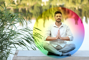 Man meditating in Lotus pose on pier near river. Rainbow bubble around him representing aura