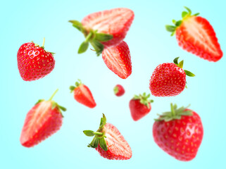 Yummy fresh strawberries swirling in air against light blue background