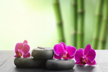 Acupuncture needles, spa stones and flowers on wooden table outdoors