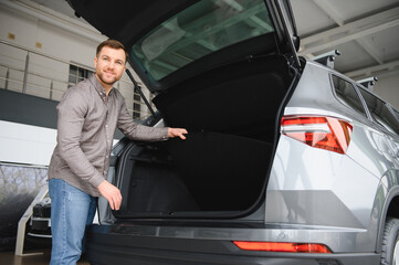 Customer examining trunk space of new car in showroom