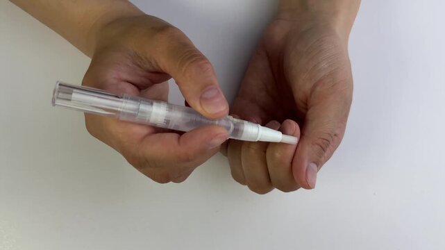 Hands apply moisturizing oil pen to fingernails, focusing on cuticle care