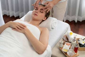 Caucasian woman enjoying relaxing anti-stress head massage and pampering facial beauty skin recreation leisure in dayspa modern light ambient at luxury resort or hotel spa salon. Quiescent