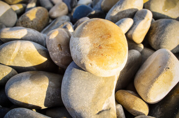 Close up view of smooth round pebbles on sunlit beach with natural textures and colors