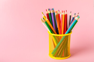 Colored pencils on a bright colored background. Equipment for coloring. Stationery for...