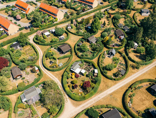 Aerial view of neatly arranged circular gardens and small cottages interlinked by pathways creating a whimsical, verdant tapestry, NÃ¦rum, Denmark.