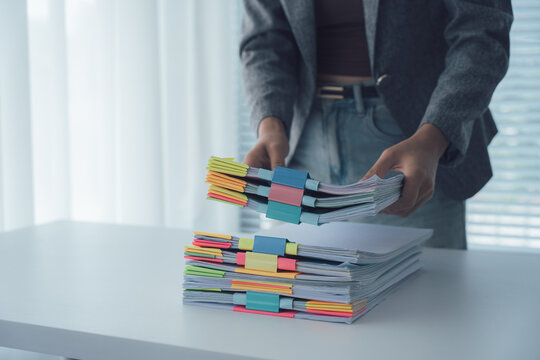 Business Documents Management: A professional organizes a stack of important documents on a pristine desk, focusing on efficiency and organization.