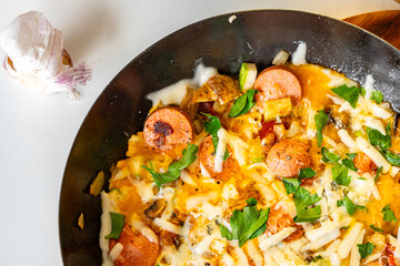 Vegetables with sausages and mushrooms are fried in a pan. The process of preparing a healthy breakfast.