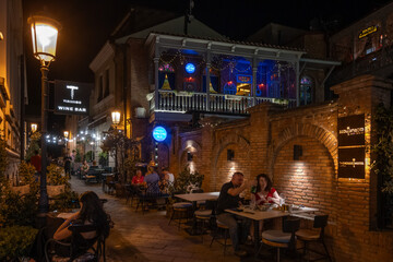 Tbilisi, Georgia - Sept 4, 2024: Night street restaurants in old Tbilisi feature red brick buildings and open air eating. Architecture reflects diverse influences and is a mix of European and Asian.