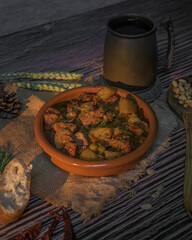 Traditional autumn beef stew with potatoes and peas in a rustic clay bowl. Warm cozy setting with...