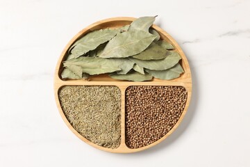 Different aromatic spices on white marble table, top view