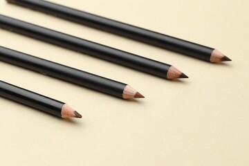Different eyebrow pencils on beige background, closeup