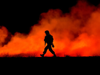 Obraz premium Military soldier walking in silhouette against fiery backdrop
