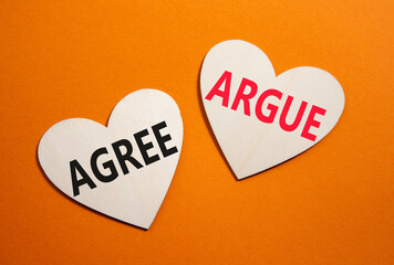 Agree or Argue symbol. Concept word Agree or Argue on wooden hearts. Beautiful orange background. Business and Agree or Argue concept. Copy space