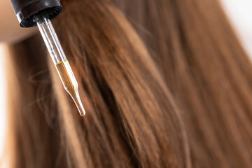 Naklejka premium Oil application on brown hair for female hair care routine
