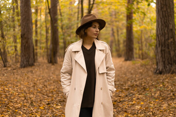 woman in an elegant hat walking alone in a quiet autumn forest.