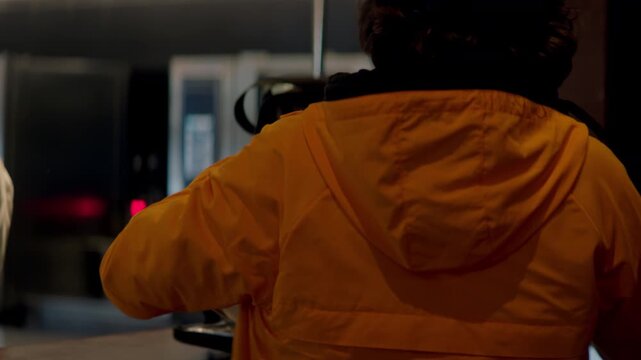 Food delivery courier in bicycle helmet entering the restaurant to pick up order for delivery. Shot with 2x anamorphic lens