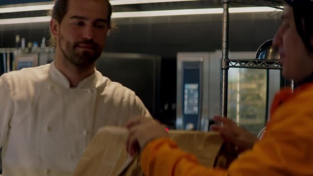 Food delivery courier in bicycle helmet entering the restaurant to pick up order for delivery. Shot with 2x anamorphic lens