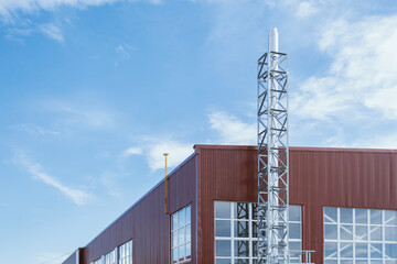 Contemporary industrial facility exterior featuring a red and white metal panel facade with silver exhaust or ventilation pipes. Concept modern industrial architecture.