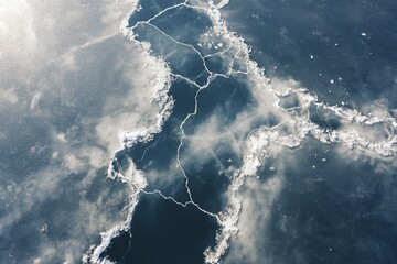 Aerial view of a frozen lake with cracks and ice formations, showcasing the beauty and fragility of winter landscapes.