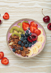 Vibrant acai bowl topped with fresh fruits like bananas, strawberries, kiwi, blueberries, cherries, crunchy granola for a healthy meal, breakfast or snack
