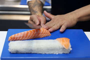 chef experto en cocina japonesa cortando salmón ahumado con un cuchillo especial para elaborar...