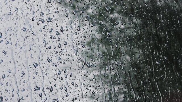 Water drops during rain roll down the side window of a car.