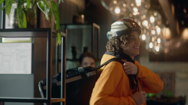Food delivery courier in bicycle helmet entering the restaurant to pick up order for delivery. Shot with 2x anamorphic lens