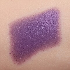 A swatch of vibrant purple lipstick on fair skin in a close up shot