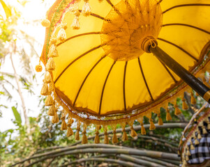 Yellow umbrella with a fringe of tassels is open in the shade