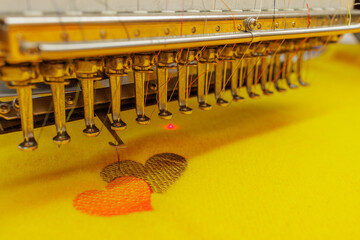 Industrial Embroidery Machine Stitching Heart Pattern on Fabric Closeup in Textile Workshop