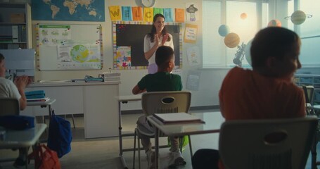 Female Teacher Introducing New Young Pupil in Front of Class Full of Primary School Students. Group of Diverse Children Sitting at the Desks, Clapping in Hands, Greeting New Classmate Before Lesson. - Powered by Adobe