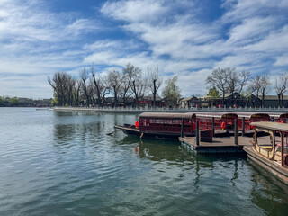 Beijing, China. Wooden tour boats docked at the lake in Shichahai, traditional Chinese architecture buildings, blue sky.