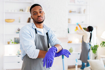 Too much domestic work. Tired black guy feeling bored of cleaning house with his girlfriend, free space. Exhausted African American man leaning on mop with miserable face expression