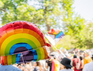 Rainbow balloon and pride flag at LGBTQ parade with people in background Empty Space