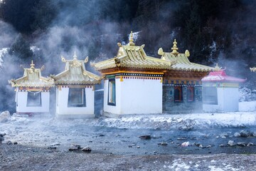 Steam rises around golden-roofed Taktsang Lhamo Monastery in snow-covered Langmusi, showcasing Tibetan Buddhist architecture in the historical Amdo region.