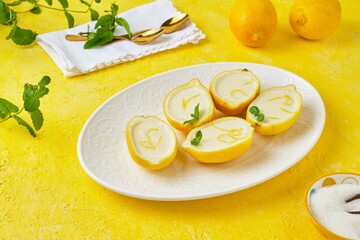 Dessert, lemon posset or citrus mousse in lemon peel halves decorated with lemon zest and mint on a...