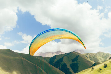 Paraglider wing against the blue sky and picturesque mountains. gliding in chegem