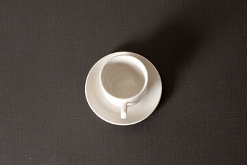 Empty white coffee cup and saucer on a two-toned table.