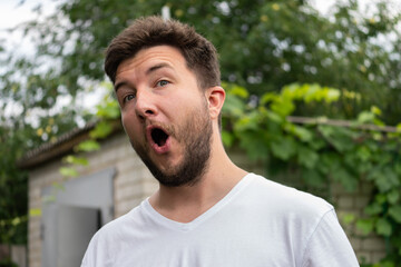 Surprised young man in garden background horizontal