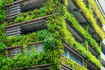 Modern building facade with lush green plants and vertical gardens promoting sustainable urban architecture in Bangkok city, Thailand. Eco friendly urban environment. Eco-friendly architecture