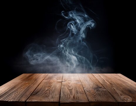 mesa de madera vacia con humo flotante sobre fondo oscuro