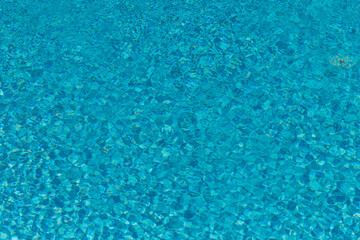 La surface d'une piscine turquoise scintillante sous le soleil d'été.