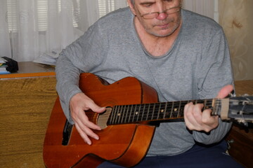 Obraz premium Middle-aged man playing old guitar visible human hands instrument house apartment dacha sitting