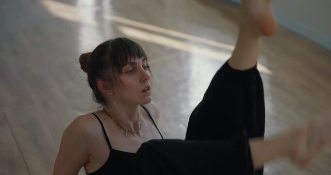 Close up of girl in a black suit performing her modern flexible slow dance in the style of contemporary parter on the floor of a choreography studio. Modern choreography