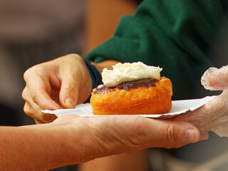 Traditional Bavarian or Czech doughnut with plum jam and cream topping being handed to a customer...