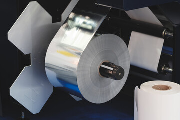 roll of plastic polyethylene film is cut by a food packaging machine. Industrial concept background.