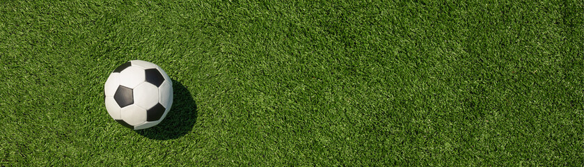 Fototapeta premium Soccer ball on field and artificial green grass. Football stadium background. View from above. Banner