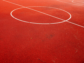 Basketball court with red surface and white lines. Court surface is clean and is in fine shape.